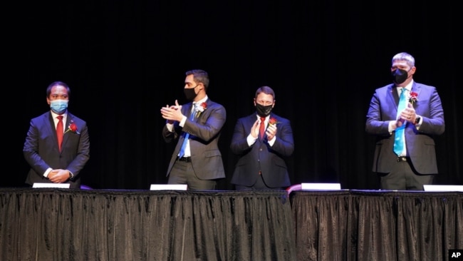 In this photo provided by Peg Shanahan, new Mayor Sokhary Chau, left, is applauded by councillors John Drinkwater, second from left, vice chair Erik Gitschier and Wayne Jenness during the Lowell City Council swearing-in ceremony, Monday, Jan. 3, 2022.