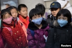 FILE - Schoolchildren wear masks as they leave school early at noon due to heavy air pollution, at a primary school in Shenyang, Liaoning province, Nov. 13, 2015.