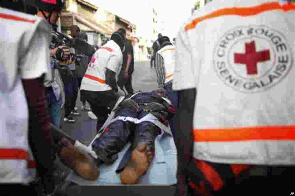 A young woman injured in violent clashes between police and anti-government protesters is transported to an ambulance by emergency responders from the Senegalese Red Cross, in central Dakar, Senegal Friday, Feb. 17, 2012. Anti-government protesters and po