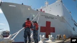 Boatswain's Mate 3rd Class Taryn Armington and Sonar Technician (Surface) Seaman Darian Joseph prepare to cast off mooring lines for the Military Sealift Command hospital ship USNS Comfort.