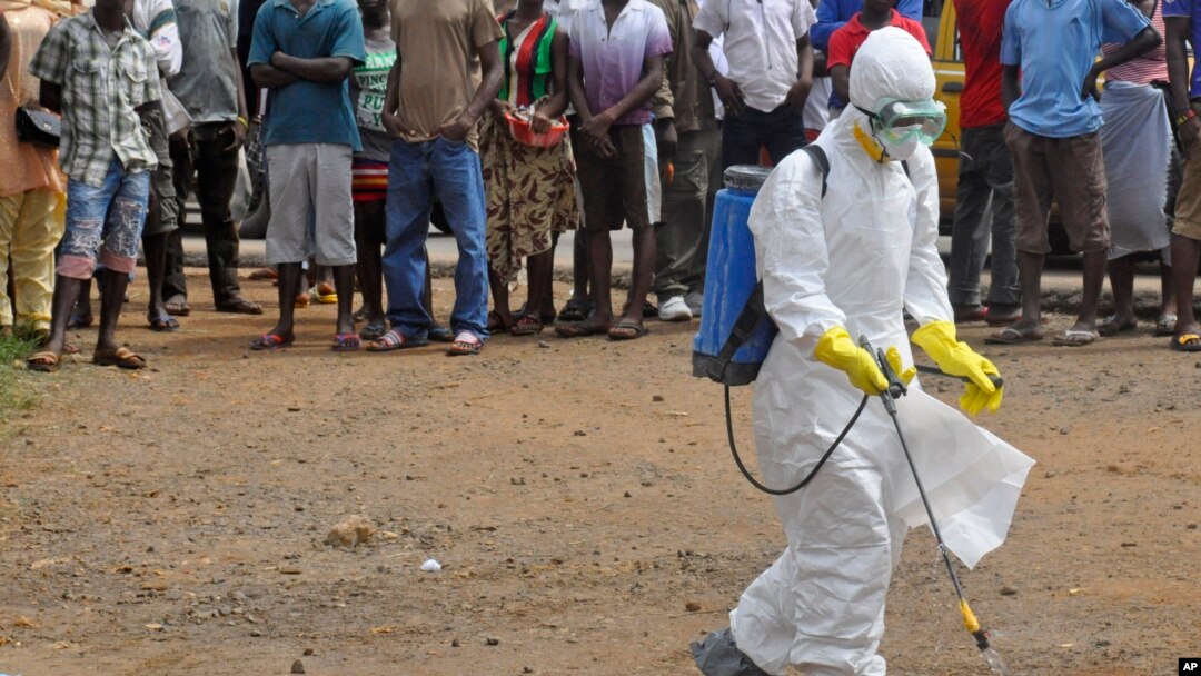 Seorang petugas medis menyemprot mayat seorang pria yang dicurigai sekarat akibat virus Ebola, dengan cairan diinfektan kimia di Monrovia, Liberia, Kamis, 4 September 2014.