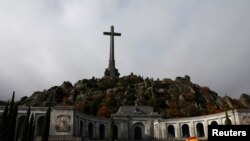 FILE - A woman holds an umbrella at the The Valley of the Fallen, the mausoleum holding the remains of former Spanish dictator Francisco Franco, outside Madrid, Spain, Nov. 20, 2018. 