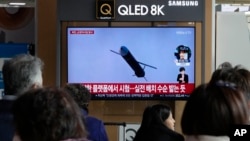 14일 한국 서울역 이용객들이 북한 순항미사일 발사 관련 TV 뉴스를 시청하고 있다.