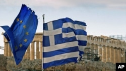 The Parthenon on the Athens Acropolis is seen behind a Greek and an EU flag atop the Greek ministry of finance, February 8, 2012.