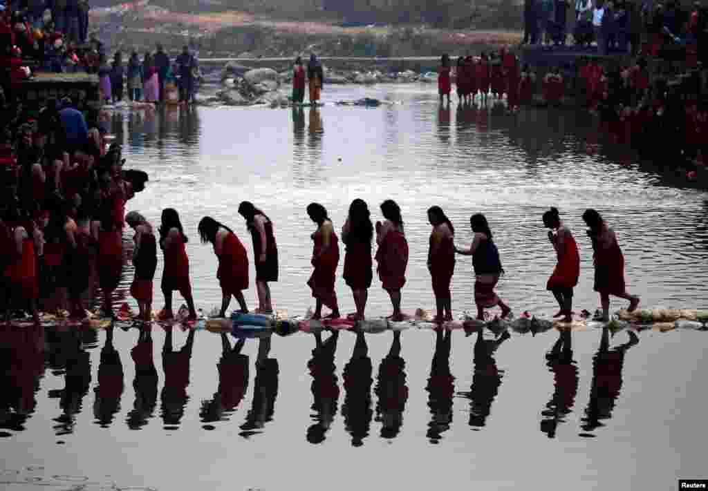 Devotees cross the Triveni River during the Swasthani Bratakatha festival in Panauti, near Kathmandu, Nepal.