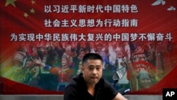 一名男子走过北京街头宣传习近平指示的各族人民大团结中国梦的广告牌。（20218年9月11日）