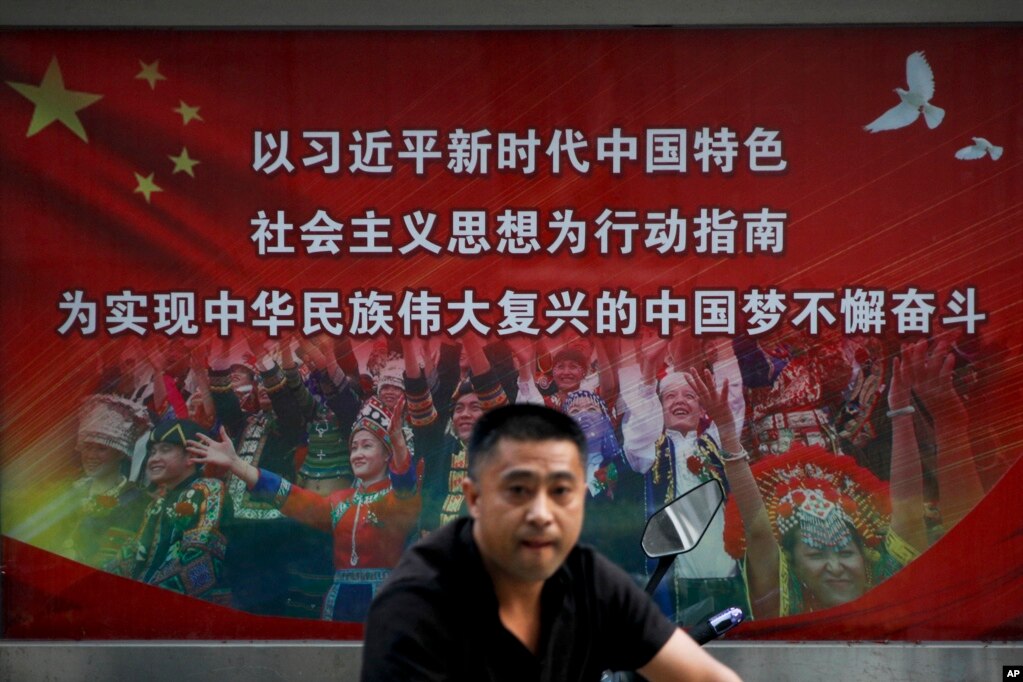 一名男子走过北京街头宣传习近平指示的各族人民大团结中国梦的广告牌。（20218年9月11日）(photo:VOA)