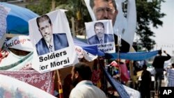 Para pendukung Presiden terguling Mesir, Mohamed Morsi memasang foto-foto Morsi berukuran besar di depan tenda mereka di 'Nasr City' (25/7). Seorang hakim Mesir telah memerintahkan dilanjutkannya penahanan Presiden terguling Mohamed Morsi atas tuduhan bersekongkol dengan kelompok militan Palestina Hamas.