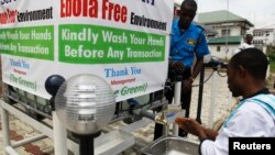 A man washes his hands at a tap outside the Green Pharmacy, Area 8, in Abuja, Sept. 1, 2014. 