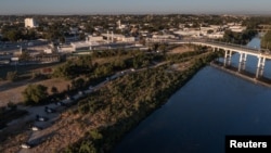 Los vehículos de las fuerzas del orden se alinean a lo largo de la frontera entre Estados Unidos y México en Ciudad Acuña, como se ve en esta fotografía aérea tomada desde Del Rio, Texas, Estados Unidos el 23 de septiembre de 2021.
