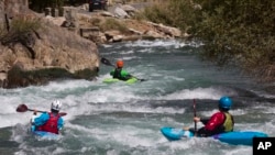 Tiga turis asing berkayak di sepanjang Sungai Panjshir di Afghanistan, sebagai ilustrasi. Tim penyelamat terpaksa mengamputasi kaki seorang pemain kayak pada akhir pekan setelah ia terjebak di celah berbatu di sungai Australia yang berbahaya. (Foto: AP)