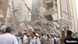 Warga Iran berkerumun di lokas gedung berlantai 10 yang roboh di Kota Abadan, iran, 23 Mei 2021. (Foto: West Asia News Agency via Reuters)