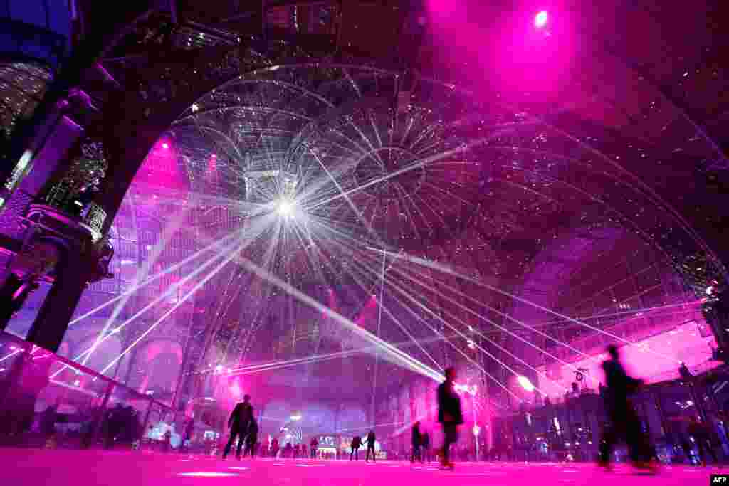 Warga bermain sepatu seluncur di atas es pada acara pembukaan di Grand Palais, Paris.