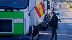 FILE - A trucker waits by a convoy of vehicles set to drive slowly during a protest though Madrid, Spain, Dec. 15, 2021. Governments worldwide are facing protests, work stoppages or other political pressure to take action against soaring inflation.