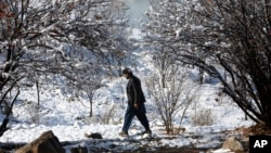 An Afghan man walks in the season's first snow in Paghman district of Kabul, Afghanistan, Jan. 4, 2017. Despite the usual harsh winters, Afghanistan security forces plan to continue their operations against the Taliban and Islamic State. 