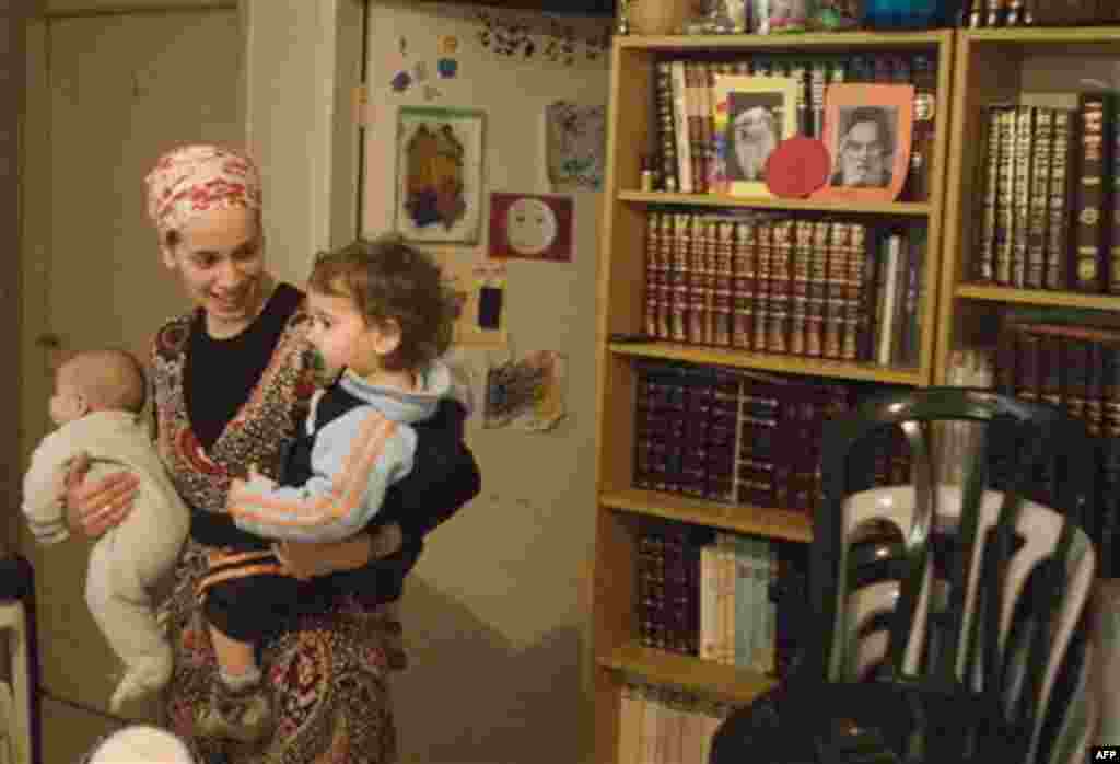 An Israeli settler who did not want to be identified holds her children inside Beit Yonatan, a building that houses seven Jewish families and a religious learning center, during clashes between Israeli troops and Palestinian youth, not seen, in the east J