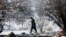 An Afghan man walks in the season's first snow in Paghman district of Kabul, Afghanistan, Jan. 4, 2017. Despite the usual harsh winters, Afghanistan security forces plan to continue their operations against the Taliban and Islamic State. 