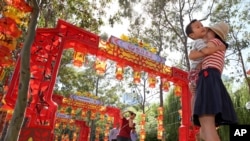 FILE - Pen Pu (center) and Chelsea Peng play with their three-year-old son Dore Peng at the Chinese Garden of Friendship in Sydney, Australia, 2015. (AP Photo/Rick Rycroft)