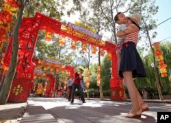 FILE - Pen Pu, center, photographs his wife Chelsea Peng, right, and their three-year-old son Dore Peng, amongst a colorful display of arches and lanterns near the Chinese Garden of Friendship in Sydney, Australia.