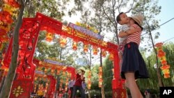 FILE - Pen Pu (center) and Chelsea Peng play with their three-year-old son Dore Peng at the Chinese Garden of Friendship in Sydney, Australia, 2015. (AP Photo/Rick Rycroft)