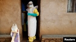 Health care workers enter a house where a baby suspected of dying of Ebola is, during the baby's funeral in Beni, North Kivu province, Democratic Republic of the Congo, Dec. 18, 2018. 