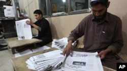 FILE - Afghan workers arrange copies of the 8AM daily newspaper in Kabul, Afghanistan.