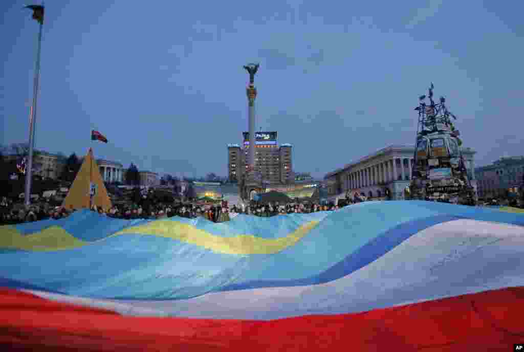 People hold huge Ukrainian, Crimean and Crimean Tatar flags during a rally in support of Ukraine's territorial integrity, in Kyiv's Independence Square, March 27, 2014.