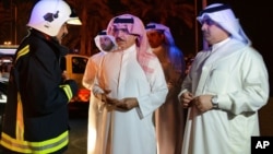 In this photo released by Bahrain News Agency, Sheikh Rashid bin Abdullah Al Khalifa, Bahrain Minister of Interior talks with a member of the emergency services, during his visit to the scene of an explosion, in Bahrain, Saturday, Nov. 11, 2017. Bahrain says an oil pipeline that exploded overnight was attacked by militants.