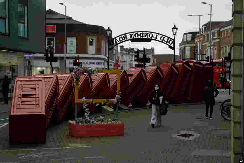 A woman walks past &quot;Out of Order&quot; a 1989 red phone box sculpture by British artist David Mach, in Kingston upon Thames, London, during England&#39;s third national lockdown since the coronavirus outbreak began.