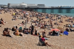 People sunbathe on the beach and cool off in the sea in Brighton on the south coast of England, May 31, 2020.