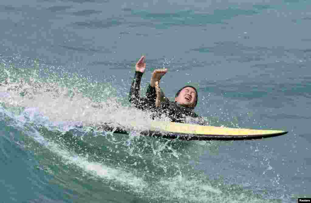 Surfer kreće prema moru, dok ljudi za vikend hrle na plažu u Santa Monici u Kaliforniji uživaju. 30. maj, 2021. ( Foto: Dejvid Svanson / Rojters )
