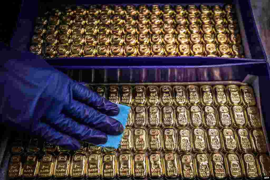 A worker polishes gold bullion bars at the ABC Refinery in Sydney, Australia. Gold prices hit $2,000 an ounce on markets for the first time, the latest surge in a commodity.