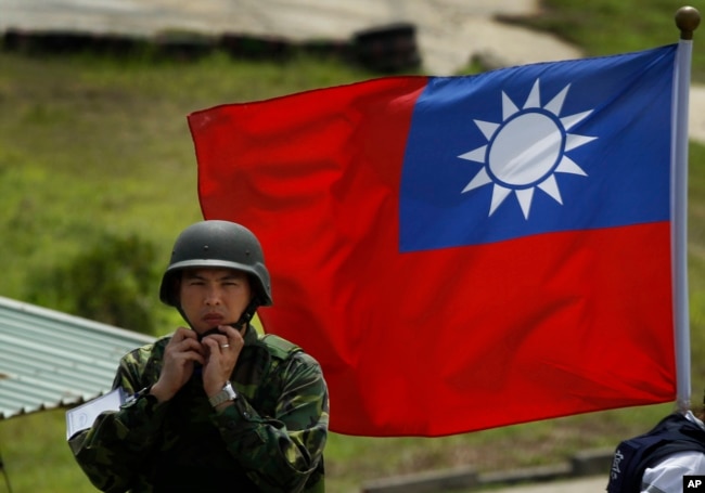 资料照：台湾旗帜前一名士兵整理自己的头盔。