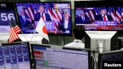 An employee of a foreign exchange trading company looks at monitors showing U.S. President elect Donald Trump speaking on TV news in Tokyo, Japan, Nov. 9, 2016. 