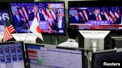 FILE - An employee of a foreign exchange trading company looks at monitors showing U.S. President elect Donald Trump speaking on TV news in Tokyo, Japan, Nov. 9, 2016. 