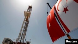 FILE - Turkish and Turkish Cypriot flags wave beside a offshore drilling tower near Famagusta, Cyprus, April 26, 2012.
