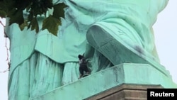 Una manifestante es vista en la base de la Estatua de la Libertad en Nueva York, el 4 de julio de 2018.