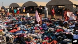 Người dân Iraq chạy lánh nạn tìm quần áo để mặc trong đống quần áo các tổ chức từ thiện cung cấp