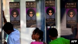 Children look through glass as fans of musician Prince enter a "Rally 4 Peace" concert in Baltimore, Maryland, May 10, 2015.