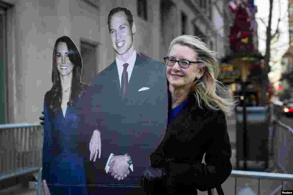 A local resident holds a cut-out of the Duke and Duchess of Cambridge, Prince William and his wife, Catherine, outside the Carlyle Hotel in New York, Dec. 7, 2014.