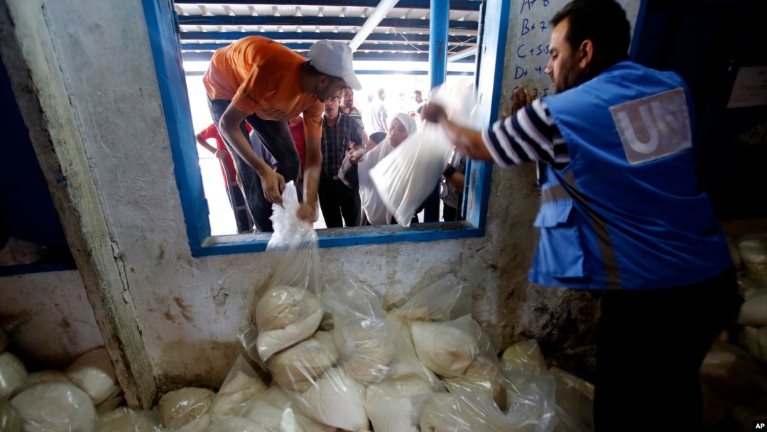 Palestinians crowd a window for food aid at a United Nations distribution center in the Shati refugee camp in Gaza City, Aug. 6, 2014. 