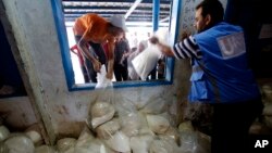 Palestinians crowd a window for food aid at a United Nations distribution center in the Shati refugee camp in Gaza City, Aug. 6, 2014. 