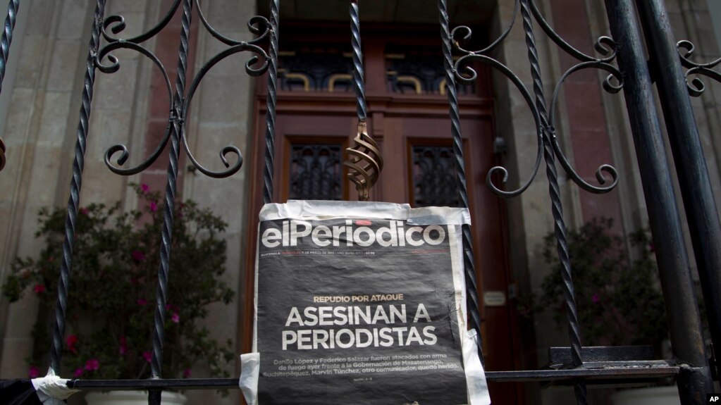 ARCHIVO - Una copia de la portada de elPeriódico, que reza "Periodistas asesinados", cuelga en una puerta principal de la Casa Presidencial durante una protesta en marzo de 2015.
