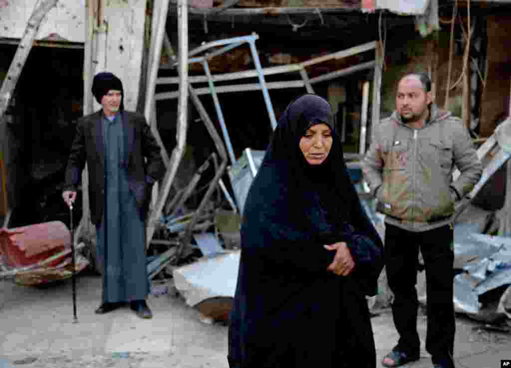 Civilians inspect the site of a car bomb attack, eastern Ur neighborhood of Baghdad, Iraq, Feb. 18, 2014.