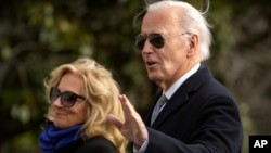 President Joe Biden gestures as he and first lady Jill Biden walk across the South Lawn of the White House, Jan. 2, 2025, in Washington, after returning from Camp David. 