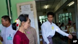 Pemimpin Liga Nasional untuk Demokrasi Myanmar, Aung San Suu Kyi, kedua kiri, tiba di TPS untuk memberikan suaranya di Yangon, Myanmar, Minggu, 8 November 2015. (AP Photo/Gemunu Amarasinghe)