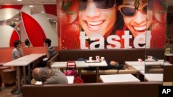 FILE - Two men sleep at night in a 24-hour McDonald’s branch in Hong Kong. The recent death of a woman at a Hong Kong McDonald’s, where her body lay slumped at a table for hours unnoticed by other diners, has focused attention on the city’s working poor a