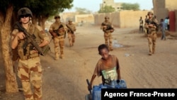 French soldiers patrolling the streets of Gao walk past a boy carrying canisters on Dec. 4, 2021.