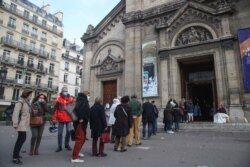 FILE - Churchgoers wearing face masks lineup outside the Notre-Dame-des-Champs church in Paris, France.