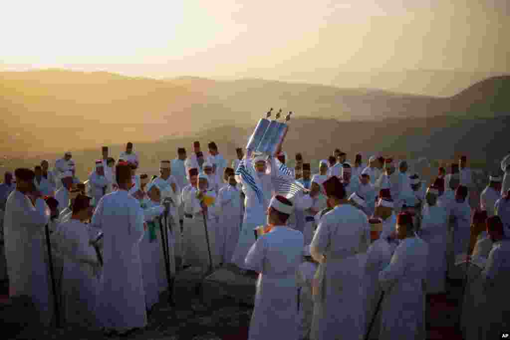 A member of the ancient Samaritan community holds up a Tora scroll as worshippers pray during the Passover pilgrimage at the religion&#39;s holiest site on the top Mt. Gerizim, near the West Bank town of Nablus.
